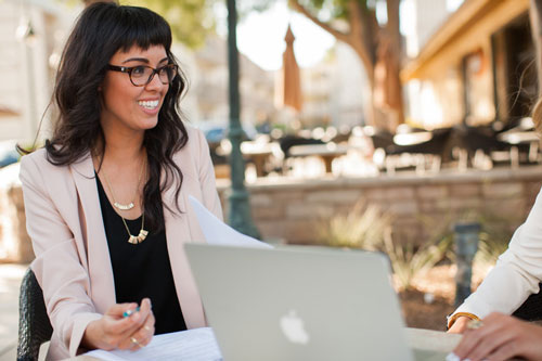 Two female CBU students gathered around a laptop