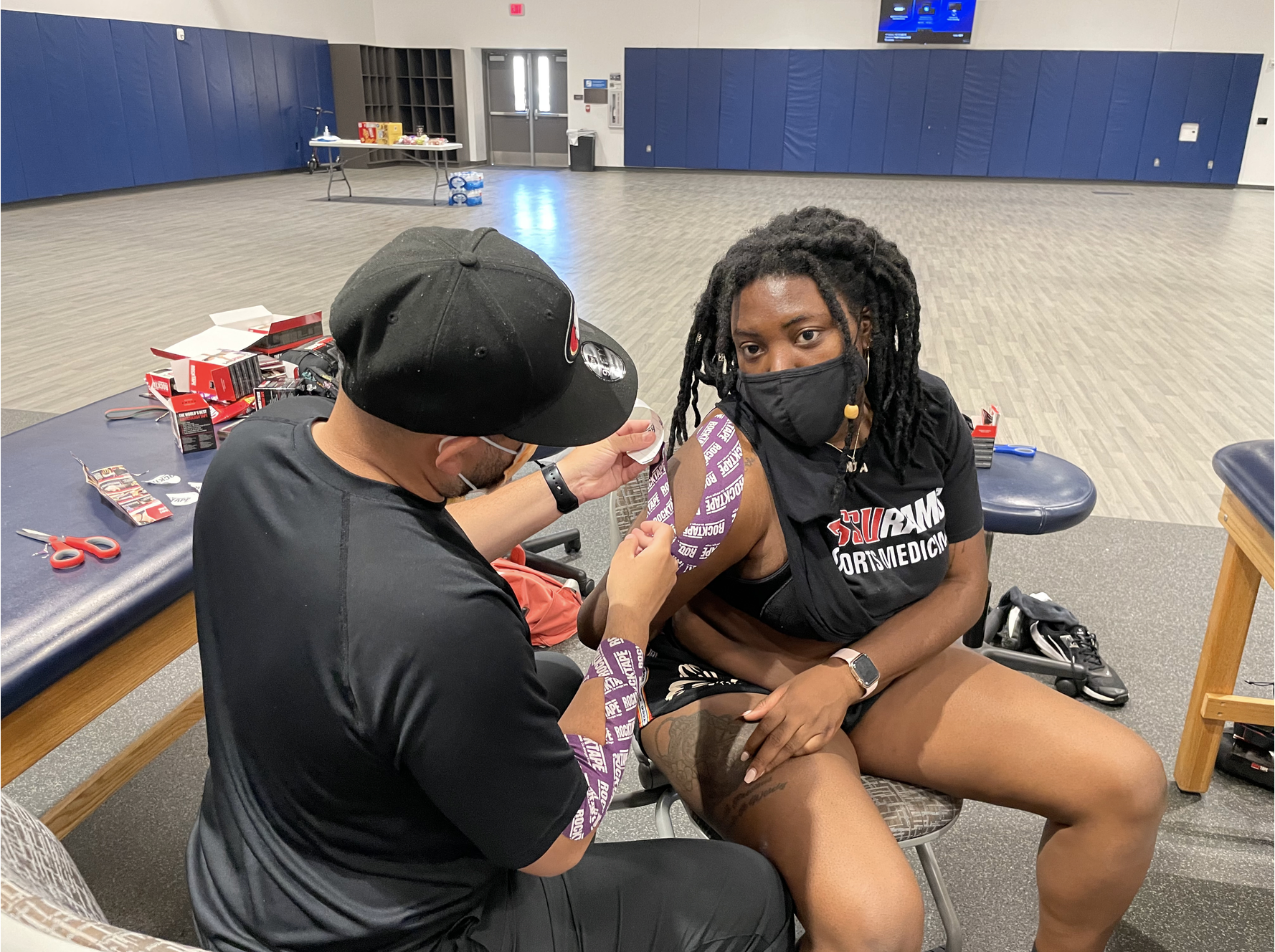 man putting tape on woman's arm