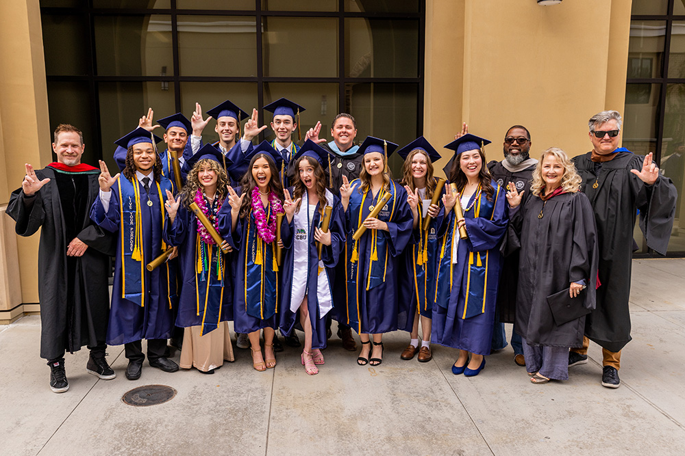 group of graduates and professors smiling for the camera