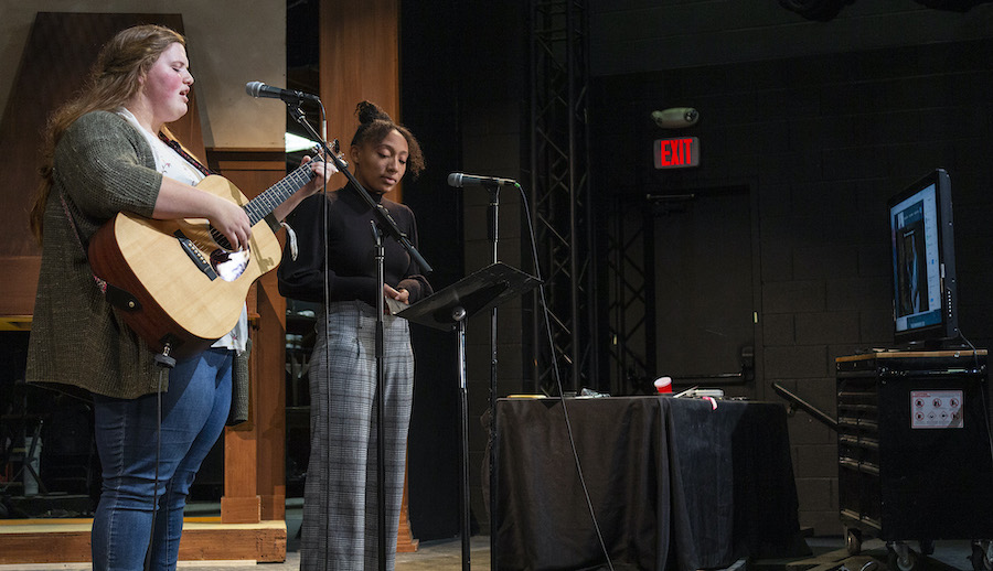 two people on stage and one is holding a guitar