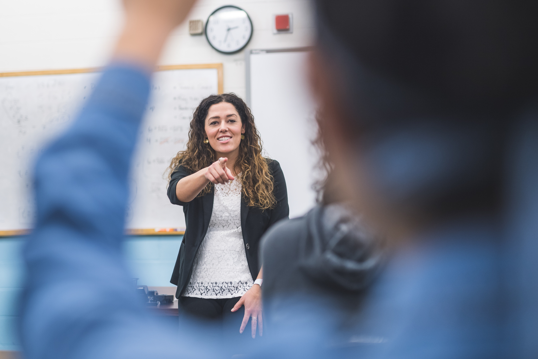 a teacher pointing at a student raising their hand