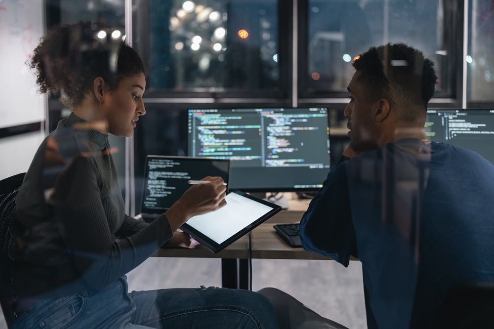 2 professionals working on computers and a tablet