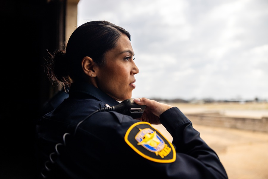 Police Officer overlooking an area while holding her radio