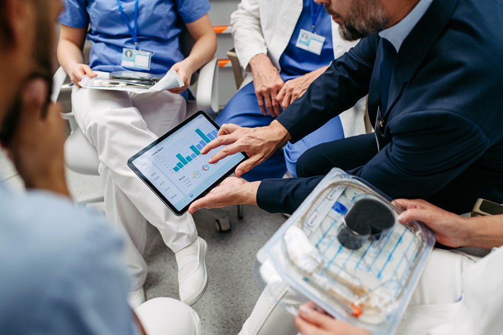 5 healthcare professionals around a tablet with data on it