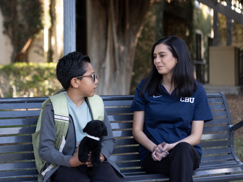 Advisor talking to a student on a bench outside