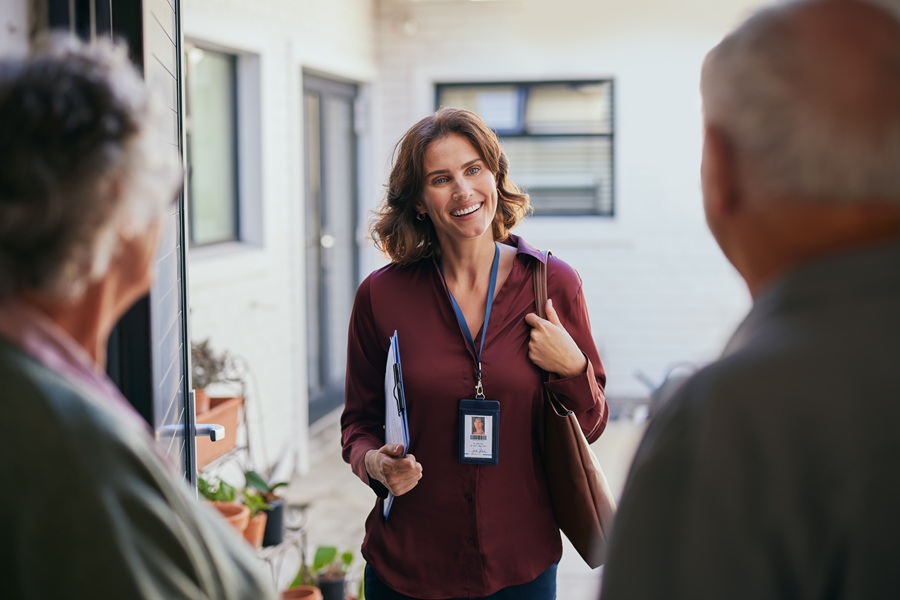2 individuals talking with a woman in the foreground in an office setting wearing a lanyard 