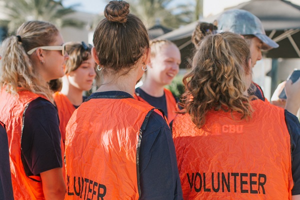 Students facing opposite direction wearing orange volunteer vests