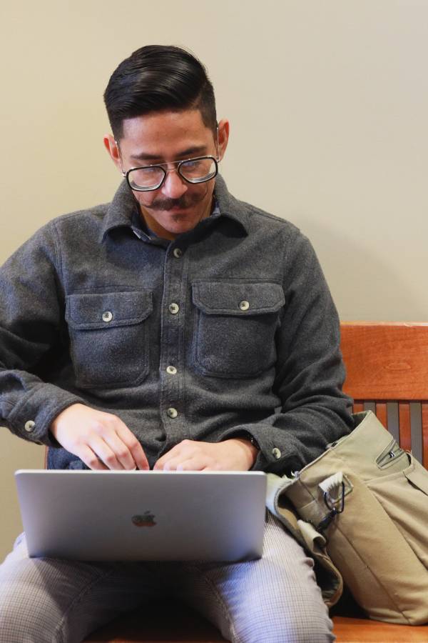 A male CBU student working on a laptop while sitting on a bench
