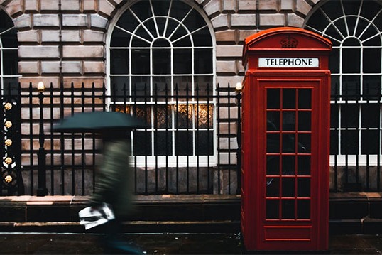 A red telephone booth on a sidewalk in London