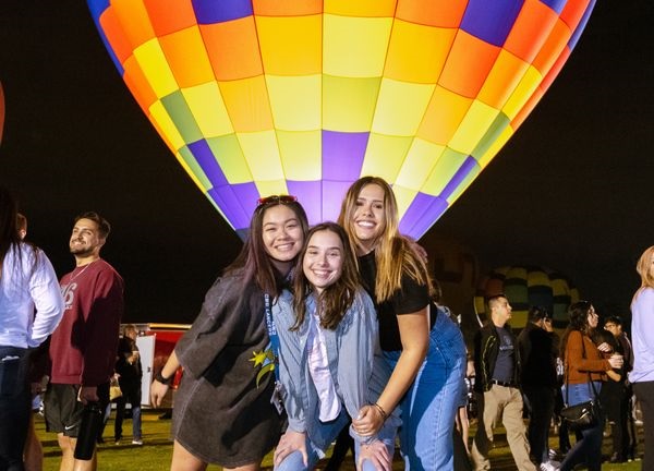 Students in front of a lighted up air balloon 